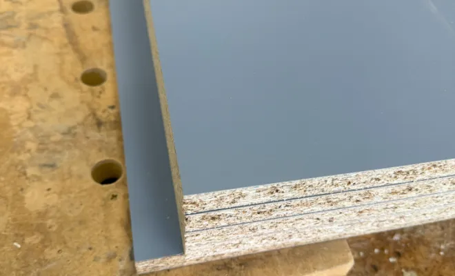 Début de la Fabrication du Dressing Client : Après avoir conçu et validé un plan 3D avec notre client, nous entamons la phase de fabrication du dressing sur mesure. La photo illustre le premier pas important : la découpe précise des panneaux de bois, essentiels pour la structure du meuble. Les panneaux, soigneusement sélectionnés pour leur qualité et leur finition en gris moderne. Cette étape marque le commencement tangible de la réalisation du projet conçu sur mesure